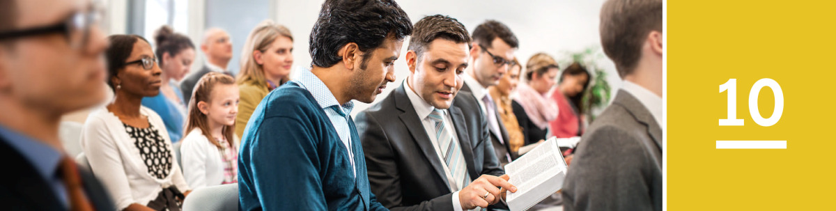 Image 1: A man looks at a scripture that a Witness shows him in the Bible during a congregation meeting of Jehovah’s Witnesses.