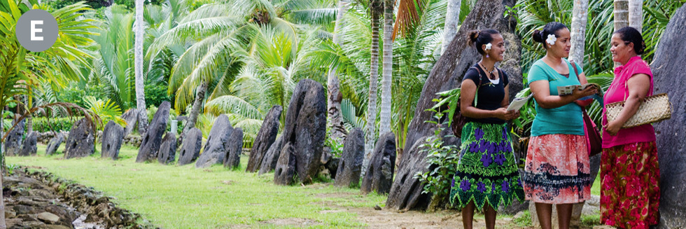Image 6: E. Two of Jehovah’s Witnesses preaching to a woman in front of large stone disks in Yap. E. Yap