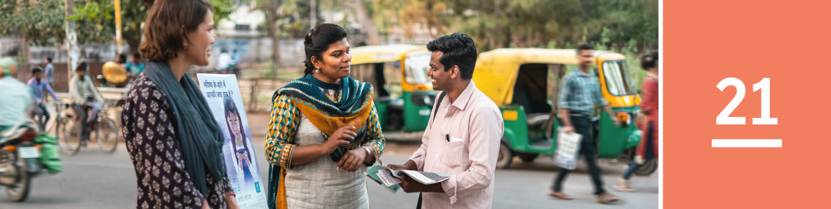 Image 1: A man on a city street talks with two of Jehovah’s Witnesses next to a literature cart.