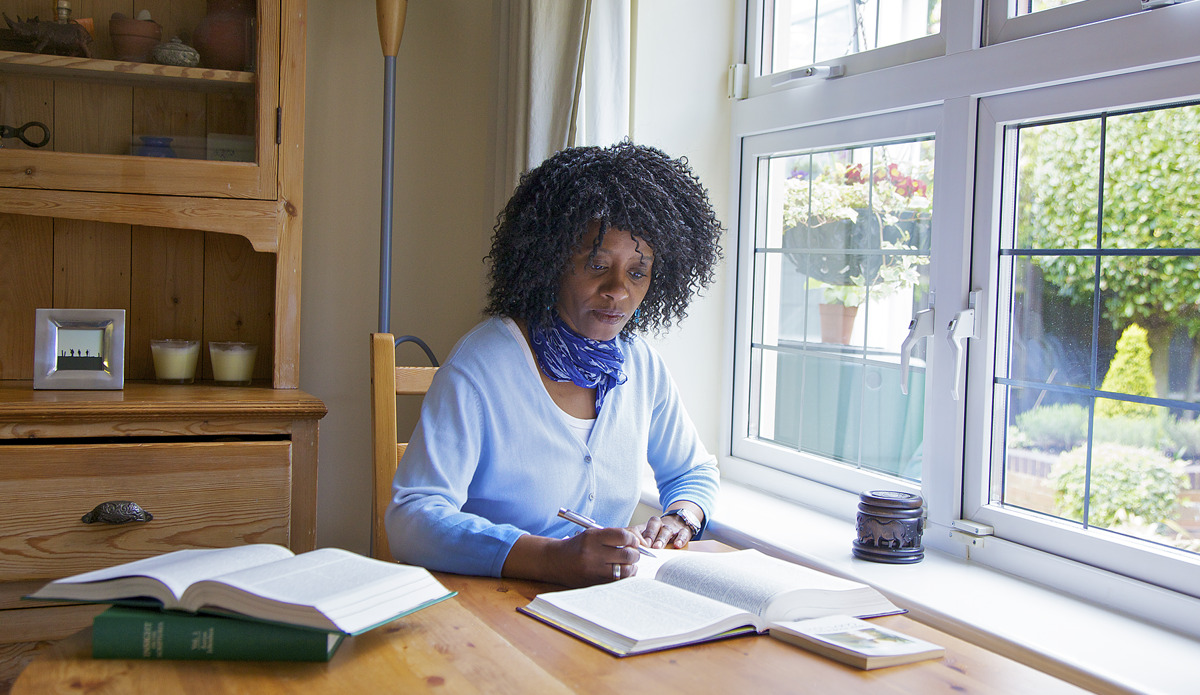 IMAGE 2 PICTURE DESCRIPTION: Rosalind John writing notes and using research publications during her personal study of the Bible.