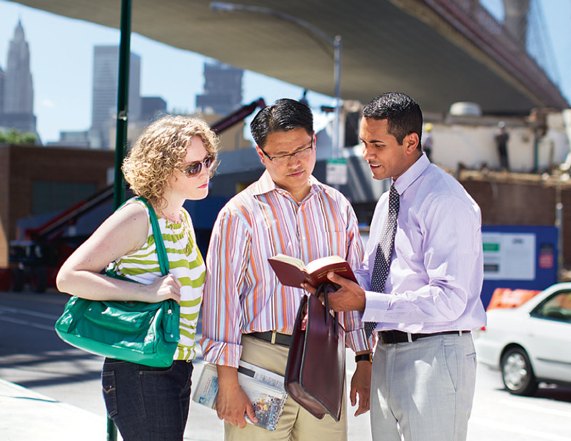 IMAGE 2: In the street, Luis reads the Bible to a couple