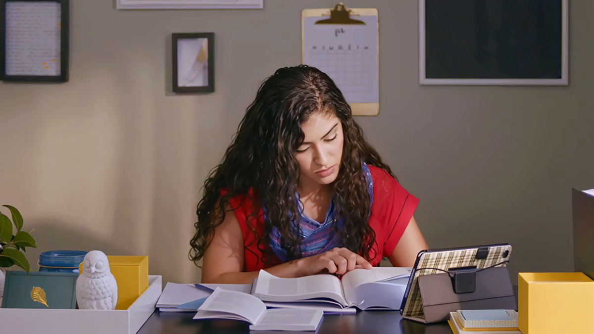 Uma cena do vídeo “Coisas Que Fortalecem a Lealdade — Autodomínio”. A irmã que luta com pensamentos negativos estuda a Bíblia, usando um tablet e um caderno.