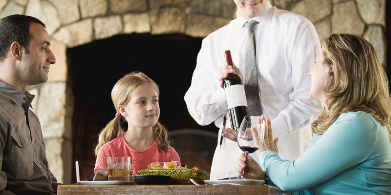 IMAGE 2 PICTURE DESCRIPTION: A little girl observes her mother refuse a waiter’s offer of more wine CAPTION: Your children will learn from your example in using alcohol